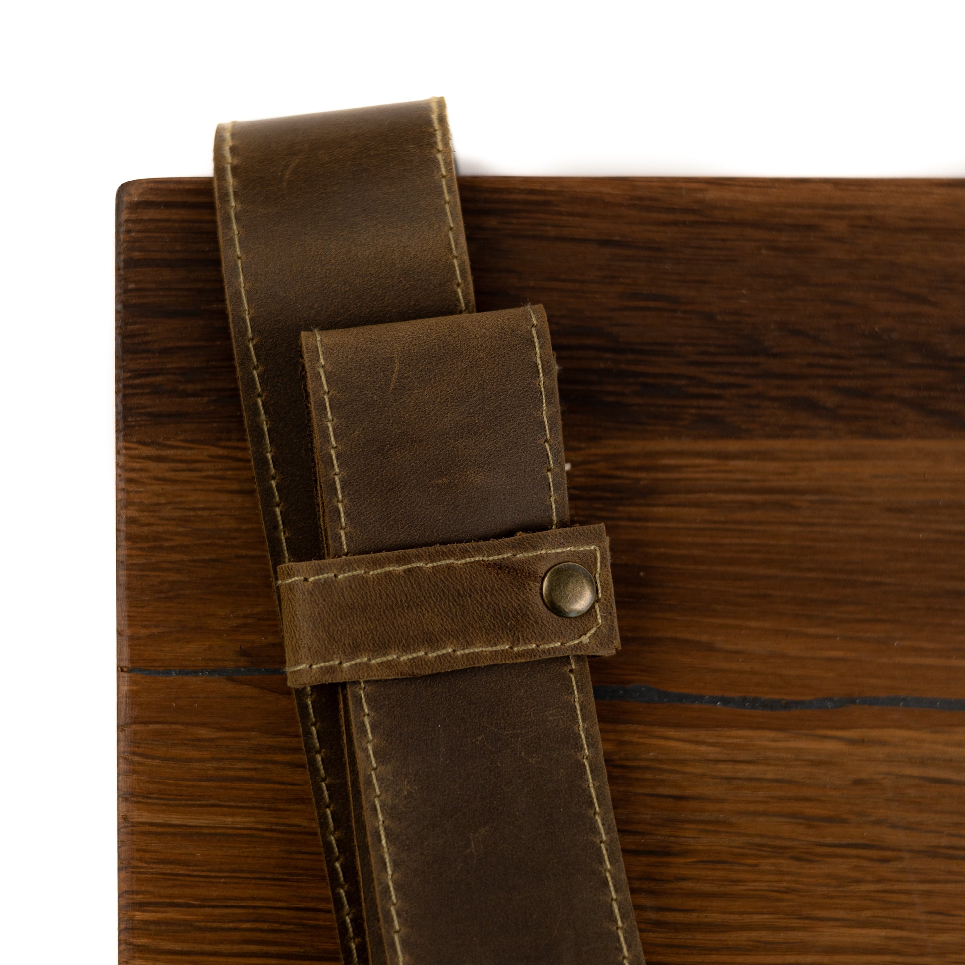 Close-up of natural oak grain and brown leather straps with metal fittings